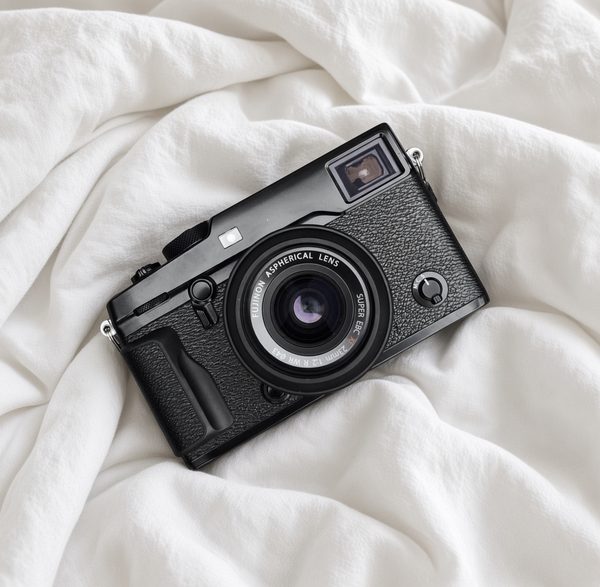 A Fuji X Pro2 with a 23mm lens resting on rumpled white sheets.